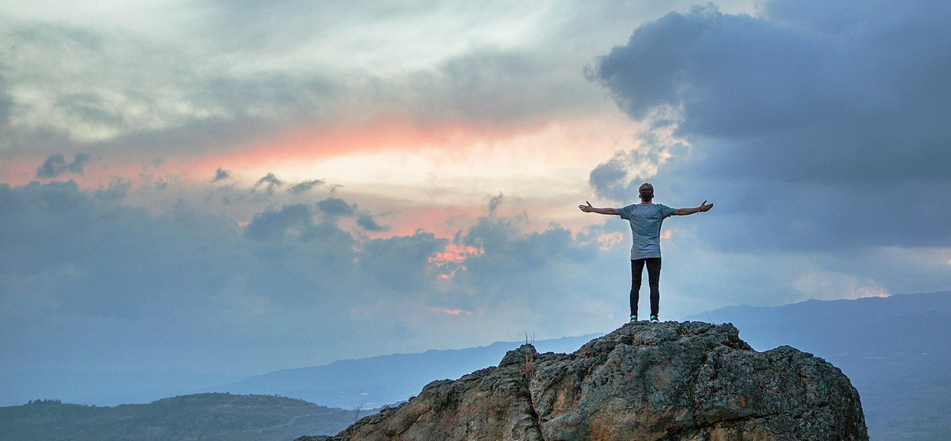 Person standing on a mountain with arms outstretched