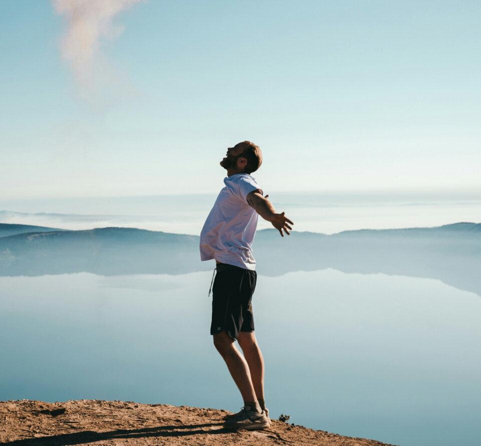 Person standing on a cliff overlooking a misty landscape